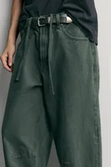 Pantalón barrel fit de mezclilla color verde militar, con efecto lavado, cinco bolsillos, cierre frontal con cremallera y botón, y detalle de pinzas en las rodillas.