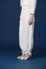 Pantalón de mujer color blanco, de corte amplio y silueta fluida, con cintura definida y puños ajustables con tiras para atar en los tobillos.
