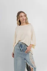 Sweater oversize de tejido liviano color blanco roto, con textura semi traslúcida, escote redondo y mangas amplias estilo murciélago.