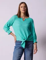 Blusa color verde agua, marca Ruby Rd, de tejido texturado con escote en V y aplique metálico. Tiene mangas largas con puños elásticos y ruedo con nudo.