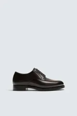 Zapato de vestir estilo Derby fabricado en piel, con horma redonda, cordones al tono y suela con ligero tacón.