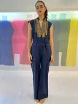 Mono largo azul marino con estampado dorado en la parte superior, cuello mao, sin mangas, con cinturón y bolsillos laterales.