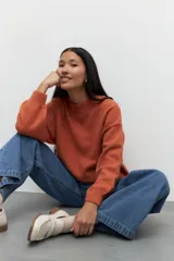 Polera de punto color naranja con mangas abullonadas, puños elastizados y cuello alto a la base.