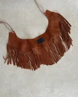 Pechera de cuero vacuno color marrón con diseño de flecos largos y tiras finas para atar. Accesorio decorativo para el cuello con terminación en punta y estilo rústico.