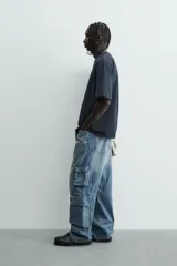 Camiseta relaxed fit color azul marino, con cuello redondo y manga corta. Presenta un estampado combinado a contraste en el delantero y la espalda. El estampado frontal es un texto en cursiva y un dibujo de tres figuras alargadas.