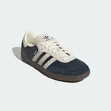 Zapatillas Adidas Samba OG con exterior de cuero azul marino y detalles en gamuza beige. Presentan las icónicas tres tiras laterales, suela de goma color marrón y el nombre del modelo en letras doradas.