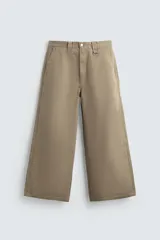 Pantalón chino de corte baggy fit, confeccionado en tejido de algodón. Presenta perneras amplias y holgadas, bolsillos frontales y traseros, con cierre de cremallera y botón.