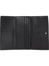 Billetera grande de Tommy Hilfiger en color negro con textura granulada, cierre de botón a presión y monograma TH metálico en tono dorado en la parte frontal.