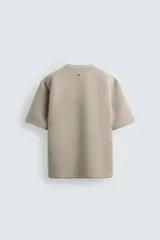 Sudadera de manga corta con corte relajado, confeccionada en tejido técnico compacto de algodón con elasticidad. Presenta cuello redondo y detalle de tacha metálica en la espalda.