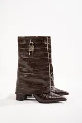 Botas de cuero marrón con estampado de cocodrilo, caña media, punta fina, taco cuadrado y candado decorativo en la parte superior.