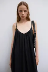 Vestido midi de color negro, confeccionado en tejido fluido, con escote en V y tirantes finos ajustables. Presenta frunces en el pecho y un volante en el bajo.