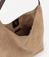 Cartera tipo hobo de gran tamaño confeccionada en material sintético efecto gamuza color tostado. Presenta una estructura flexible, asa única en tono contrastante y cierre mediante botón a presión.