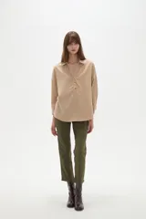 Blusa holgada de poliéster color beige, con cuello camisero, escote en V con botones frontales y mangas largas.