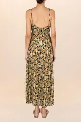 Vestido largo con estampado de hojas en tonos ocre, negro y blanco. Presenta escote en V profundo con ajuste de cordón bajo el busto, tirantes delgados ajustables y abertura frontal en la falda.