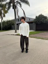 Sweater de punto con diseño bicolor y texturas combinadas, presenta un lado de tejido liso y otro con trenzado vertical. Posee cuello redondo, corte holgado y una etiqueta decorativa en el frente.