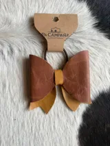 Moño para el pelo confeccionado en cuero, con diseño artesanal en tonos marrón y tostado.