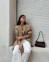 Collar con dije colgante de forma orgánica e irregular, acabado dorado, suspendido de un cordón negro de algodón natural.