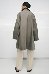 Trench oversize de Zara Woman Collection, confeccionado en hilatura de algodón. Presenta cuello solapa, manga larga, bolsillos delanteros y cierre frontal con botones ocultos bajo solapa.