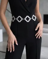 Cinto de cadena metálica plateada con eslabones y dijes en forma de trébol de cuatro hojas decorados con strass brillante.