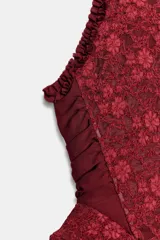 Corset bordó de cuello halter con hombros descubiertos, confeccionado con combinación de tejidos con patrón floral, detalles de volados en las sisas y bajo en peplum. Cuenta con cierre en la espalda con cremallera.