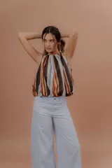 Musculosa de algodón con cuello redondo, sin mangas y diseño abullonado en la parte inferior. Presenta un estampado de rayas verticales en tonos marrones, naranjas, celestes y negros.