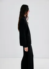 Chaleco negro de punto, de corte recto y largo, con cuello alto.