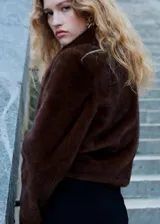 Chaqueta de piel sintética en color marrón chocolate, con cuello solapa, cierre frontal y mangas largas. Presenta una silueta recta y un acabado suave.