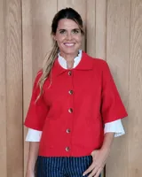 Cardigan de lana lambswool color rojo, con cuello tipo polo, cierre frontal de botones y mangas cortas con terminación acanalada. Presenta bolsillos frontales y diseño de punto liso.