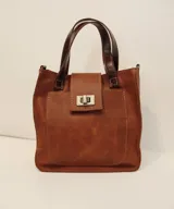 Cartera marrón de cuero con doble asa corta y cierre con solapa y broche metálico.