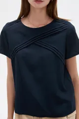 Blusa de viscosa color natural, con cuello a la base, manga corta y detalle de plisado cruzado en el frente. Presenta un corte holgado.