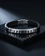 Pulsera masculina de diseño moderno, compuesta por una banda central de acero inoxidable con patrón geométrico estilo griego y laterales de goma negra.