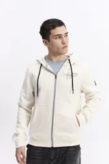 Campera con capucha y cierre frontal, color crema, con bolsillo canguro. Presenta un estampado de texto en el pecho y detalles en el puño.