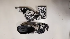 Sandalias de tacón alto y ancho, confeccionadas en piel con acabado de pelo y estampado animal print de vaca en tonos marrones y blancos, con tiras anchas en el empeine.