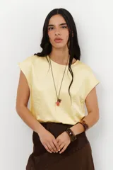 Blusa de lino con acabado satinado metalizado, color amarillo claro, de cuello redondo y mangas cortas con caída natural.