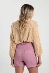 Blusa amarilla con estampado floral, cuello redondo con lazo y mangas largas abullonadas.