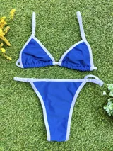 Bikini de dos piezas color azul eléctrico con ribete blanco. El corpiño es de estilo triángulo con tirantes finos regulables y la bombacha es colaless regulable con tiras laterales finas.