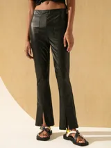 Pantalón negro de cuero en la parte delantera y lycra en la parte trasera, con corte ajustado y aberturas en el ruedo.