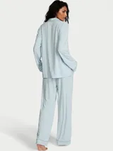 Pijama largo de modal color celeste, compuesto por una camisa de manga larga con cuello solapa, botones frontales y bolsillo en el pecho con aplique de corazón de margarita, y pantalón largo de corte recto con cintura elástica.