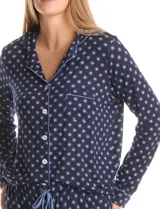Conjunto de pijama compuesto por una camisa de manga larga con cuello solapa, cierre frontal con botones y bolsillo aplicado, y un pantalón con cintura elástica y lazo de ajuste. Presenta un estampado de motivos circulares sobre fondo oscuro.