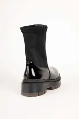 Bota baja de mujer estilo paddock, color negro, con suela track gruesa y caña de tejido elástico.