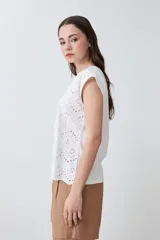 Blusa blanca de algodón con frente de tela broderie, cuello redondo y mangas cortas con diseño de hombros caídos.