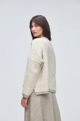 Cardigan de tejido de punto con textura, silueta boxy y cuello en V. Presenta cierre frontal con botones y detalles de terminación en contraste de color en los bordes.