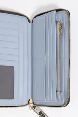 Billetera rectangular de cuero vacuno negro con cierre perimetral de cremallera metálica dorada. Incluye una correa de muñeca de tela con el logo de la marca estampado y el logo metálico dorado aplicado en el frente.