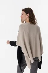Poncho de tejido de punto con diseño oversize y aberturas laterales. Presenta un acabado con destellos brillantes y cuello redondo amplio.