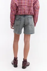 Bermuda de denim negro tipo jeans, con tiro medio, bolsillos traseros con bordado en contraste y ruedo desflecado.