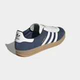 Championes Adidas Gazelle Indoor, color azul marino con tres franjas y detalles en blanco. Presentan un exterior de gamuza y cuero sintético, forro blanco y suela de goma traslúcida color caramelo.