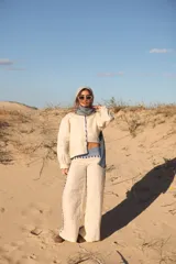 Pantalón de lino de corte ancho y tiro medio, color natural, con detalles de bandas laterales y cintura en estampado rayado azul y marrón.