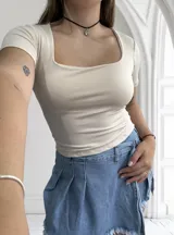 Remera negra ajustada al cuerpo, con escote cuadrado y mangas cortas.