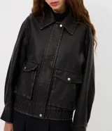 Campera de estilo urbano con corte oversized, confeccionada en poliuretano con base de poliéster. Presenta cuello clásico, cierre frontal con botones a presión, mangas largas y dos bolsillos frontales con tapa. El bajo cuenta con elástico para un mejor ajuste.