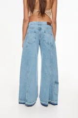 Jean de denim celeste de tiro alto y silueta wide leg, con costuras marcadas, bolsillos funcionales, bolsillo trasero inferior con bordado y terminación desflecada en el ruedo.